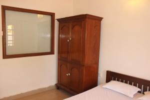 a bedroom with a wooden cabinet and a mirror at Cozy Candolim Apartment fully furnished for five adults in Candolim +25 photos