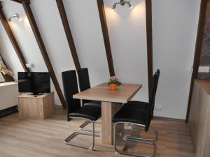 een tafel en stoelen in een kamer met een tv bij Ferienhaus im Nordschwarzwald - Nurdachhaus in Waldrandlage in Schellbronn