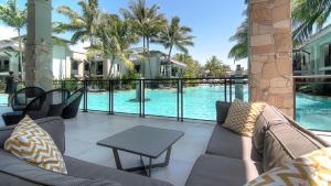 a patio with a couch and a table next to a pool at Luxury Apartments at Temple Resort and Spa Port Douglas in Port Douglas