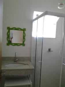 a bathroom with a sink and a mirror and a shower at Village Verano Guarajuba in Guarajuba