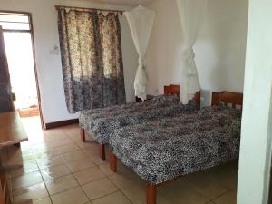 a bedroom with two beds and a window at Mama Pierina Restaurant and Annex in Morogoro +10 photos