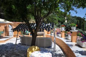 un tavolo e sedie sotto un albero in giardino di Ponte Rossa Apartments a Paleokastritsa