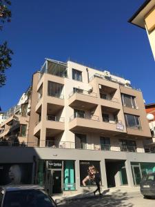 a tall building with a person walking in front of it at Apartments Park Place in Sandanski