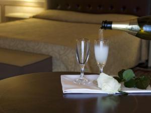 a person pouring champagne into two glasses on a table at Hotel Manganelli Palace in Catania