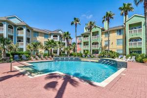 a swimming pool in front of a building with palm trees at The Dawn on Galveston Beach in Galveston