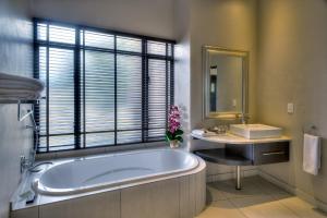 a bathroom with a tub and a sink and a mirror at Legend Simba Safari - Legend Golf Safari Resort in Golders Green