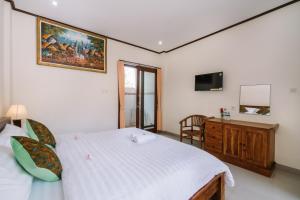 a bedroom with a bed and a dresser and a television at Sari Nusa Inn in Nusa Lembongan