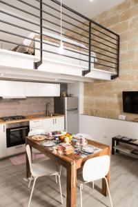a kitchen with a wooden table and white chairs at Sulla roccia dei Sassi in Matera