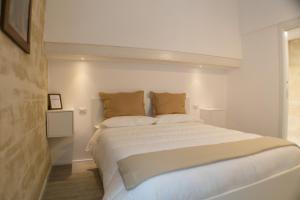 una camera da letto con un grande letto con lenzuola e cuscini bianchi di Sulla roccia dei Sassi a Matera