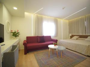 Un dormitorio con una cama y un sofá rojo. en Margoa Hotel Netanya, en Netanya