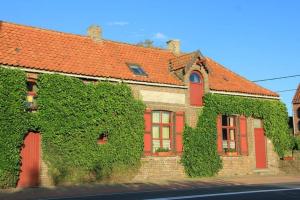 una casa cubierta de hiedra con puertas rojas y ventanas rojas en Polder 27, en Oudenburg