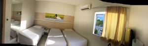 um pequeno quarto com 2 camas e uma janela em Hotel Veneza em Cuiabá