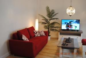 salon z czerwoną kanapą i telewizorem w obiekcie Schöne Ferienwohnung zentral gelegen w Kilonii