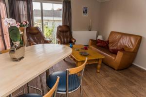 a living room with a table and leather furniture at Chaletparc Krabbenkreek Zeeland - Chalet 6 in Sint Annaland +9 photos