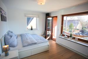 a bedroom with a bed and a window with a balcony at Appartementanlage Wieben in Sankt Peter-Ording