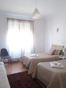um quarto de hotel com duas camas e uma janela em Guest House Guerra Junqueiro em Lisboa