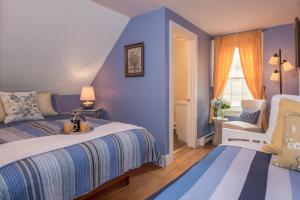 a blue bedroom with a bed and a chair at The Lincoln Inn & Restaurant At The Covered Bridge in Woodstock