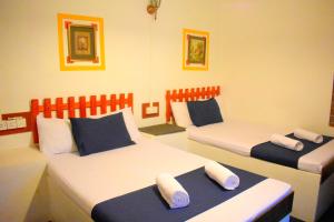 a bedroom with two beds with blue and white pillows at Selagala Resort in Anuradhapura