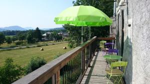 einen Balkon mit einem grünen Sonnenschirm, Stühlen und einem Tisch in der Unterkunft La Truelle in Seyne