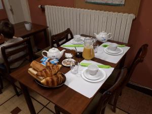 a table with a breakfast of bread and orange juice at H&ocirc;tel Le Lithana in Pontorson