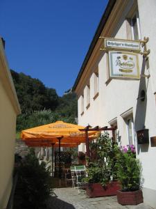 a building with an orange umbrella and tables and chairs at Pension Schrägers in Königstein an der Elbe