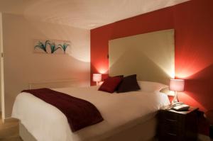 a bedroom with a large white bed with red walls at Haveli Hotel in Hensol