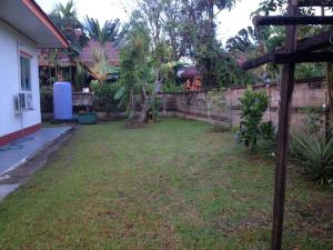 un patio trasero con una valla y un patio de césped en Janson's House en Ban Mae Kon