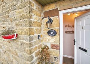 a stone wall with a clock and a door at Host & Stay - View Point Apartment in Hinderwell