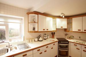 a kitchen with white cabinets and a sink and a window at Host & Stay - View Point Apartment in Hinderwell