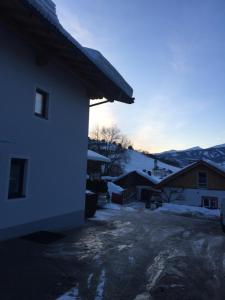dom ze śniegiem na ziemi obok budynku w obiekcie Ferienwohnung Imbach w Kaprunie