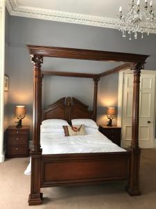 a large bed with a wooden frame in a bedroom at Fernlea spacious apartment in Arbroath