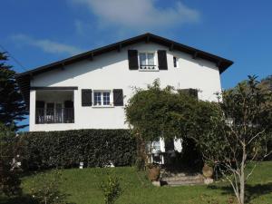 une maison blanche avec des fenêtres noires et un arbre dans l'établissement Euskadi, à Bidart