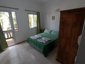 Un dormitorio con una cama verde con toallas. en Merlion en Mar de las Pampas