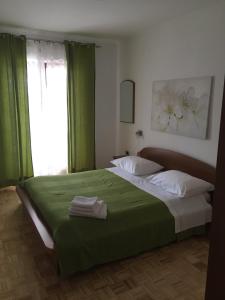 a bedroom with a bed with green curtains and a window at Apartment Vrenjak in Portorož