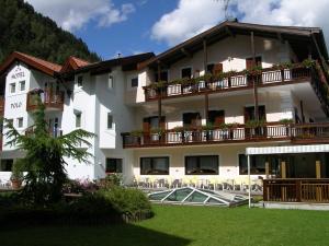 um grande edifício branco com mesas e cadeiras em Hotel Al Polo em Ziano di Fiemme