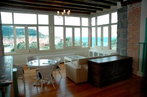 a living room with a table and chairs and windows at Hotel Villa Itsaso in Lekeitio