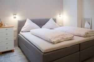 a bedroom with a bed with white pillows and a dresser at Haus Ambiente in Reil