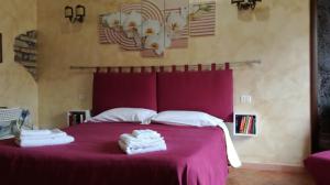 Un dormitorio con una cama morada con toallas. en La Mensa Ponderaria, en Tívoli