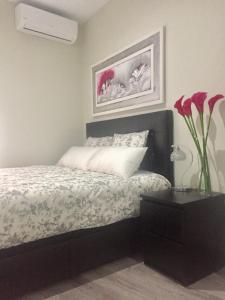 ein Schlafzimmer mit einem Bett und einer Vase mit Blumen in der Unterkunft Apartamento doña María Coronel Sevilla in Sevilla