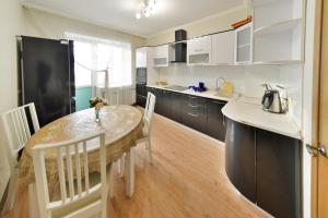 a kitchen with a table and chairs and a black refrigerator at Akbulak Town Lux in Astana