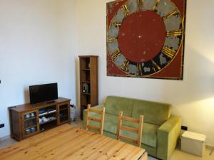 a living room with a green couch and a clock on the wall at Due Agosto Apartments in Bologna