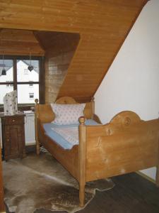 a bedroom with a wooden bed in a attic at Stierstall-Suite Pension Wahlenau in Wahlenau
