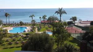 Una vista de un resort con piscina y el océano. en TORREMOLINOS CARIHUELA 1ª LINEA PLAYA, en Torremolinos