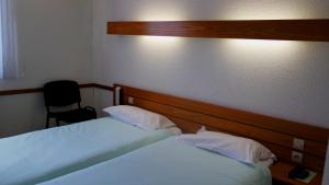 een slaapkamer met 2 bedden en een stoel bij Appart'hôtel Le Tulipier in Cransac