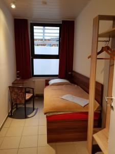 Habitación pequeña con cama y ventana en Hostel Gästehaus zum Padre en Goch