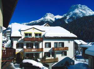 a building with snow on the roof with a mountain at Hotel Conrad in Scuol
