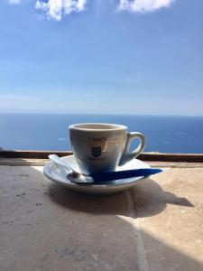 a coffee cup sitting on a plate on a table near the ocean at Le nid d aigle in Éze