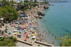 a crowd of people on a beach with umbrellas at Apartamento Nerja Beach in Nerja