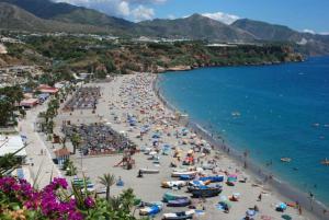 a beach with a lot of people and the ocean at Apartamento Nerja Beach in Nerja