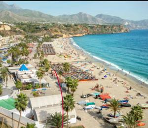 a beach with a lot of people and the ocean at Apartamento Nerja Beach in Nerja